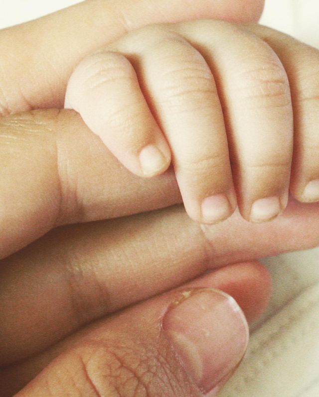 La mano de una recién nacida agarra el dedo de su mamá